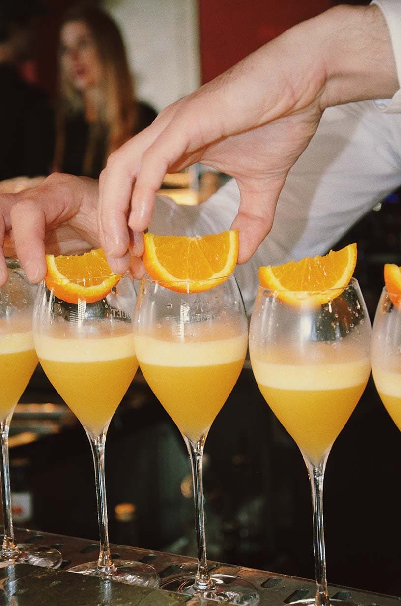 Frisch zubereitete Mimosas mit Orangenscheiben beim B. Just Bread Mimosa Morning Club