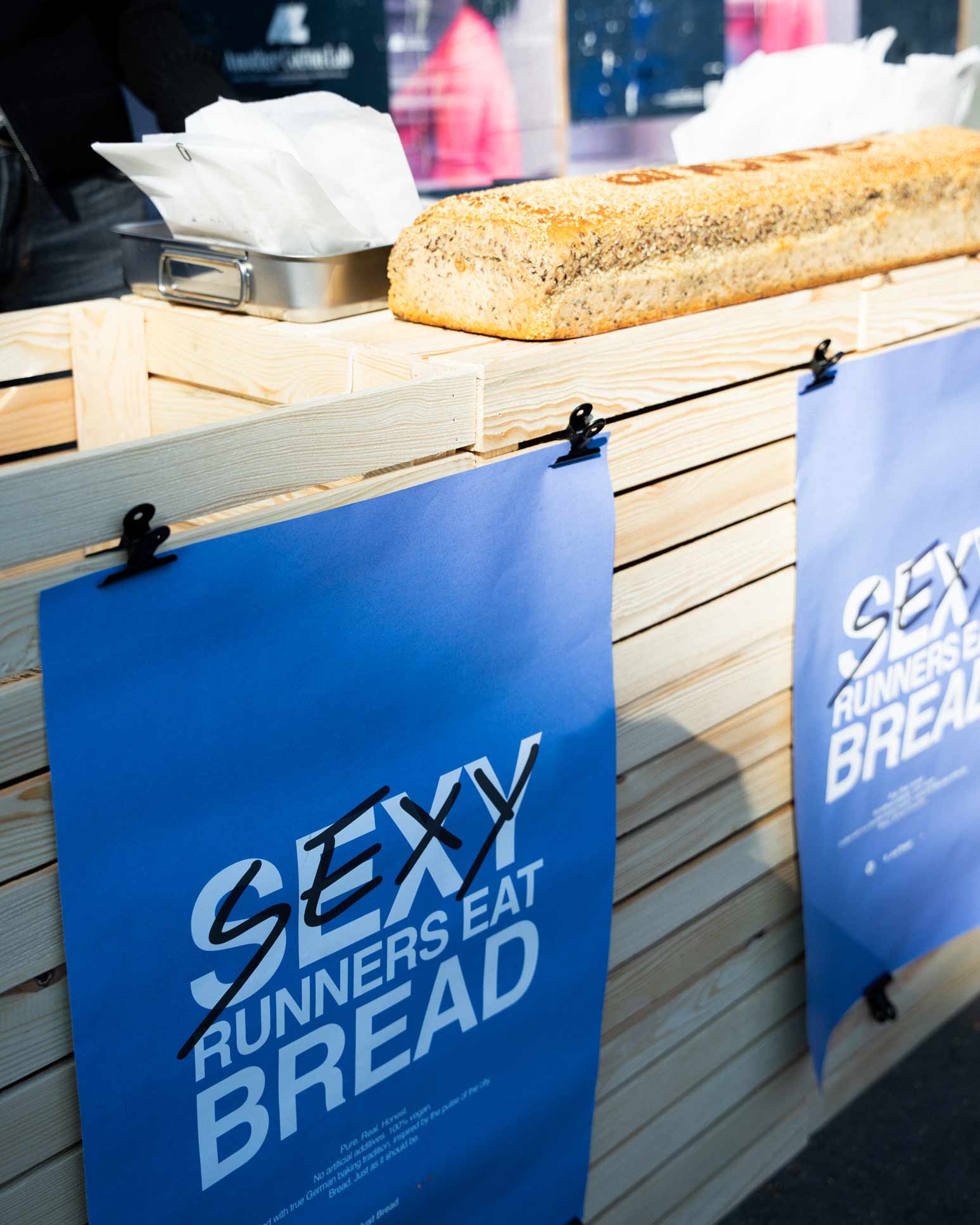B. Just Bread Brot auf einem Holzstand mit blauen Kampagnenplakaten
