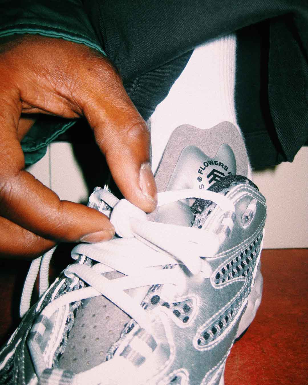 Detailaufnahme eines weißen Flowers for Society Sneakers beim Schnüren