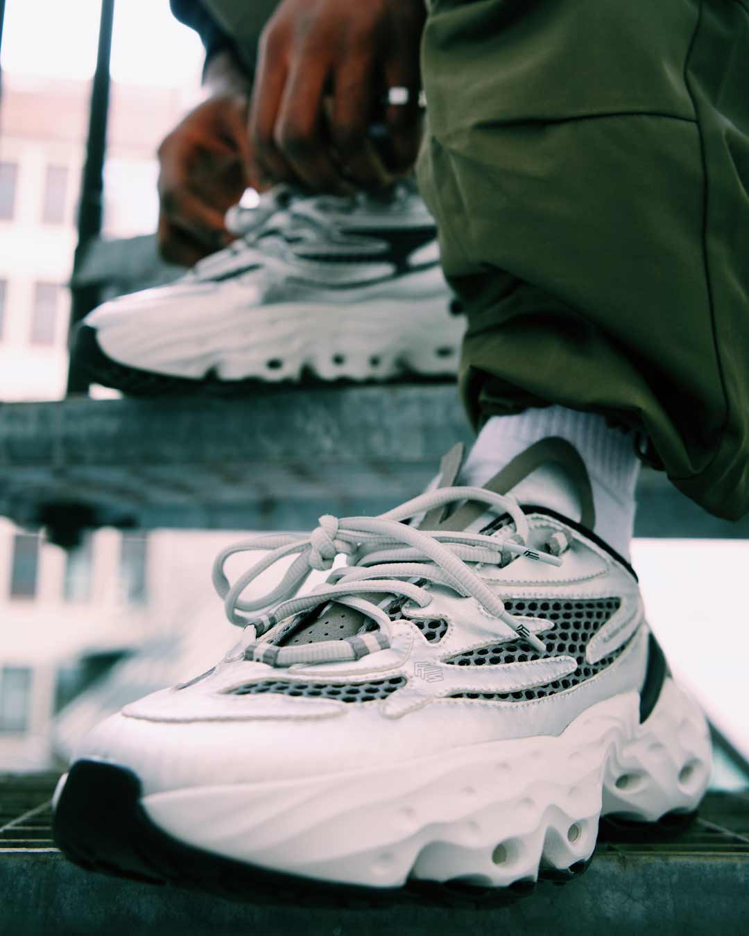 Weiße Flowers for Society Sneakers an einer Treppe mit urbaner Kulisse