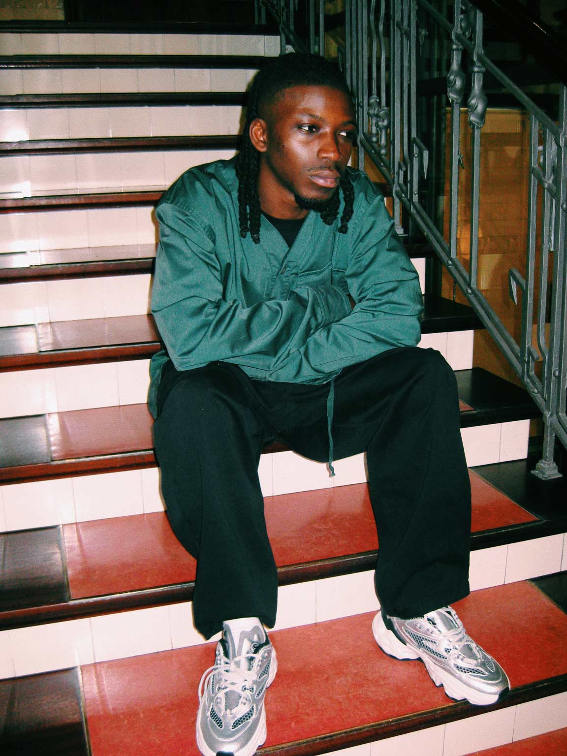 Person in grüner Kleidung und weißen Sneakers auf einer Treppe