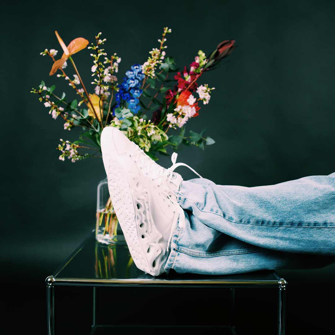 Weiße Flowers for Society Sneakers vor einem bunten Blumenstrauß