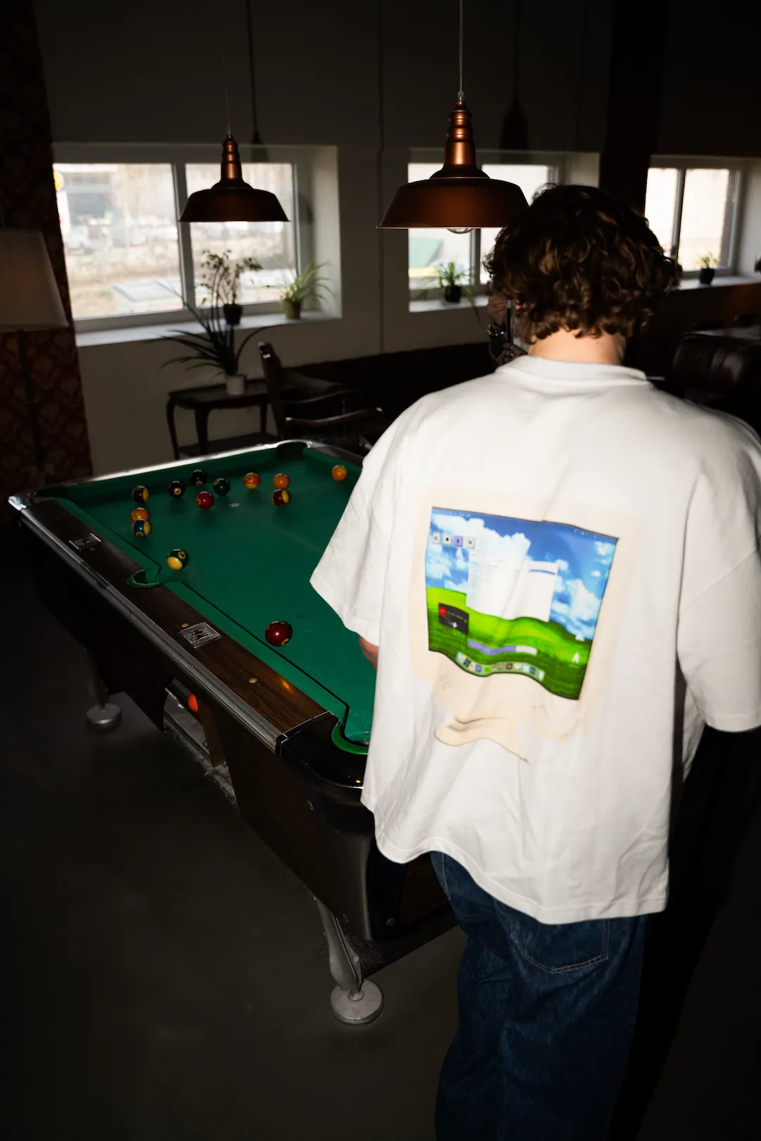 Person im GIGI and Friends Shirt vor einem Billardtisch mit grafischem Computermotiv auf dem Rücken