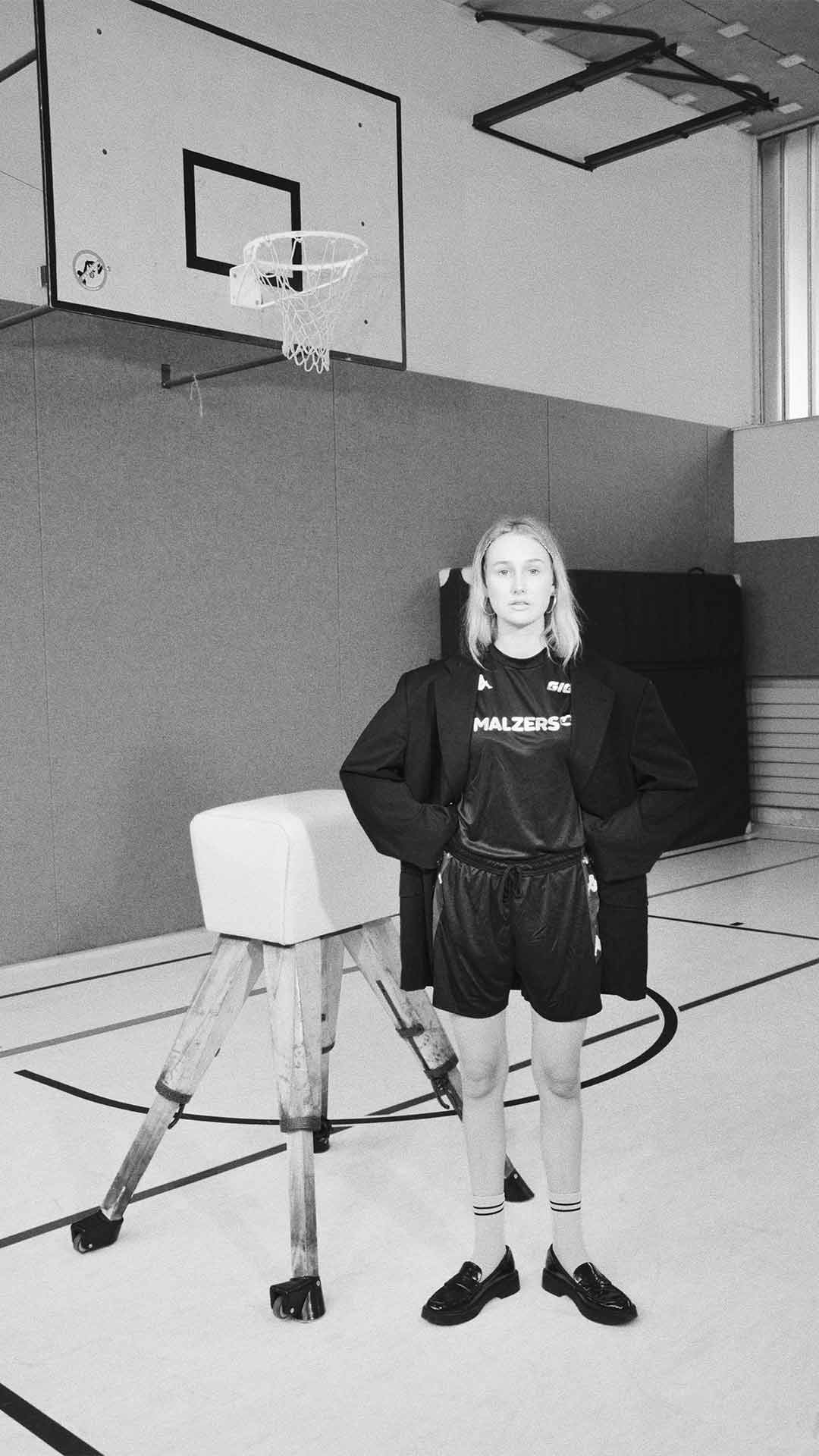 Person im Malzers Running Shirt in einer Turnhalle vor einem Basketballkorb