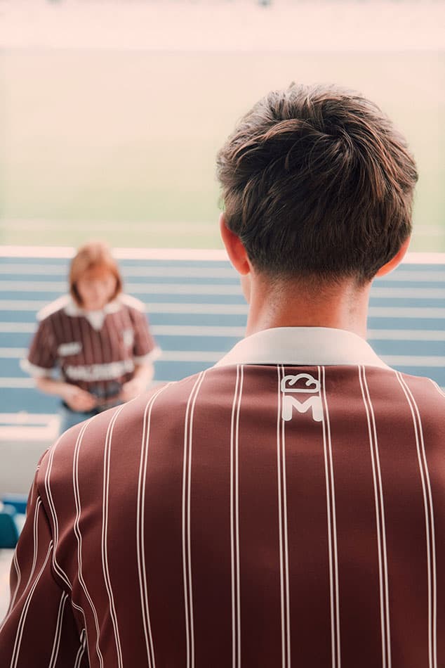 Rückansicht eines Läufers im braunen Malzers Running Jersey auf einer Laufbahn