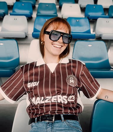 Läuferin im Malzers Running Jersey mit Sonnenbrille auf einer Stadiontribüne