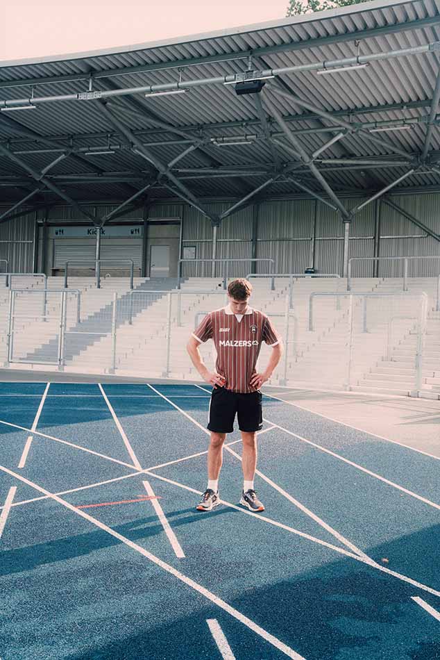 Läufer im Malzers Running Jersey auf einer Laufbahn vor einer Stadiontribüne