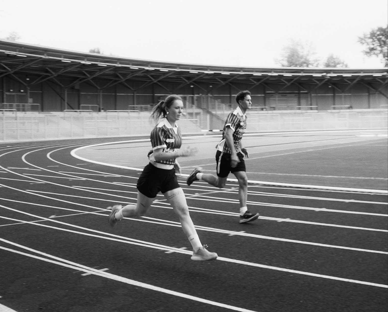 Zwei Läufer im Malzers Running Jersey beim gemeinsamen Lauf auf einer Stadionbahn